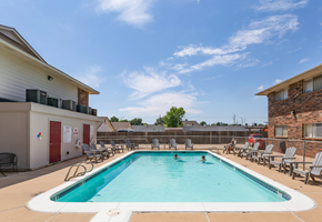 Tulsa apartment for rent - A swimming pool surrounded by lounge chairs and buildings.