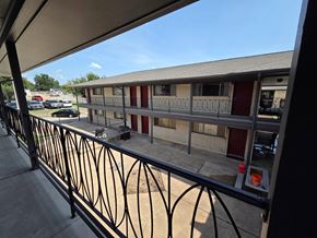 Tulsa apartment for rent - A balcony with a black railing overlooks a parking lot and a building.