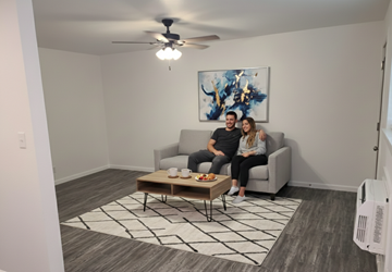Tulsa apartment for rent - A man and woman are sitting on a couch in a living room with a painting on the wall and a coffee table in front of them.