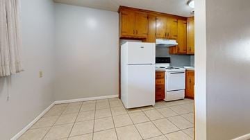 Tulsa apartment for rent - A kitchen with a white refrigerator and wooden cabinets.