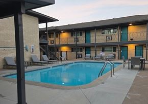 Tulsa apartment for rent - A swimming pool is surrounded by lounge chairs and umbrellas.