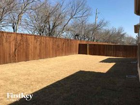 Grand Prairie house for rent - A backyard with a wooden fence and trees in the background.