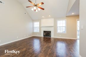 Clarksville house for rent - A spacious living room with a fireplace and a ceiling fan.