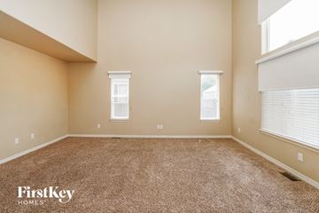 Fountain house for rent - a spacious living room with carpet and two windows