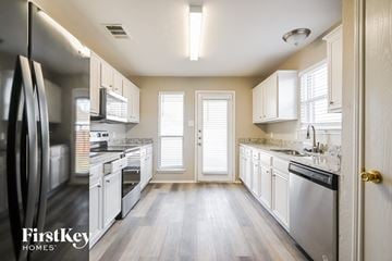 Forney house for rent - a kitchen with white cabinets and stainless steel appliances