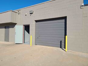 Tulsa apartment for rent - A grey garage door is closed and there is a yellow pole in front of it.