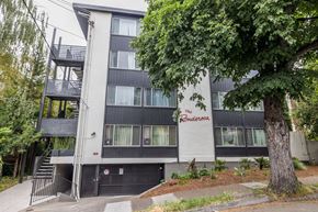 Oakland apartment for rent - A black and white building with a tree in front of it.