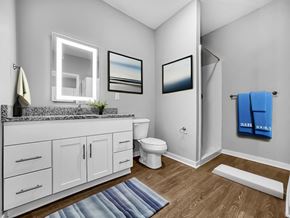 Pleasant Hill apartment for rent - A bathroom with a white toilet, a sink with a mirror above it, and a blue towel hanging on the door.
