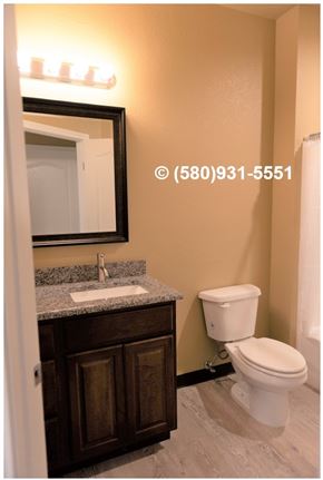 Durant apartment for rent - A bathroom with a toilet, sink, and mirror.