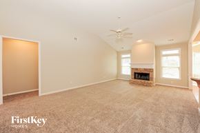 Cumming house for rent - A spacious living room with a fireplace and a carpeted floor.