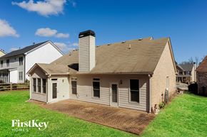 Cumming house for rent - A house with a brown roof and a chimney is surrounded by a grassy area.