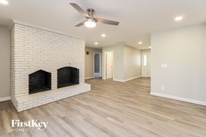 Lewisville house for rent - A spacious room with a fireplace and a ceiling fan.