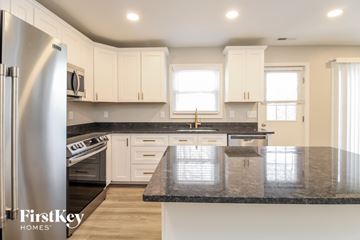 Lewisville house for rent - A kitchen with a black granite countertop and white cabinets.