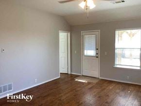 Waxahachie house for rent - an empty living room with wood floors and a white door