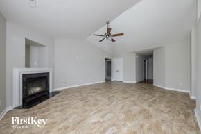 Winston Salem house for rent - an empty living room with a fireplace and a ceiling fan