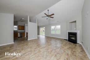 Winston Salem house for rent - an empty living room with a fireplace and a ceiling fan