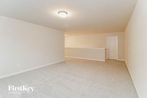 High Point house for rent - A spacious, empty room with a carpeted floor and a single light fixture on the ceiling.