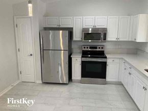 Cape Coral house for rent - a kitchen with white cabinets and a stainless steel refrigerator