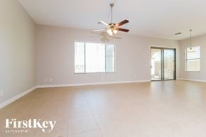 Goodyear house for rent - A spacious room with a ceiling fan and sliding glass doors.