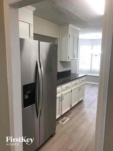 Gastonia house for rent - a kitchen with a stainless steel refrigerator and white cabinets
