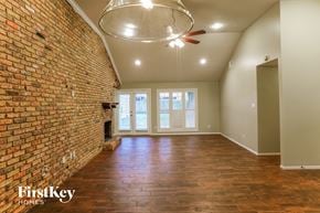 Houston house for rent - an empty living room with a brick wall and a ceiling fan