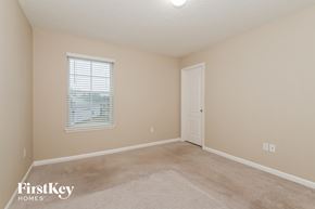 Jacksonville house for rent - a bedroom with beige carpet and a white door and window