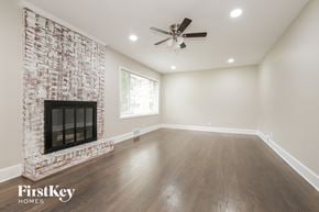Winston Salem house for rent - a living room with a brick fireplace and a ceiling fan