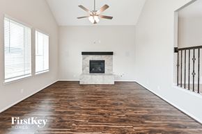 Baytown house for rent - an empty living room with a fireplace and a ceiling fan
