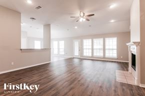 Joshua house for rent - A spacious room with wooden floors and a fireplace.