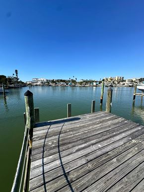 Maderia Beach apartment for rent - A wooden dock extends into a calm body of water with a city skyline in the distance.