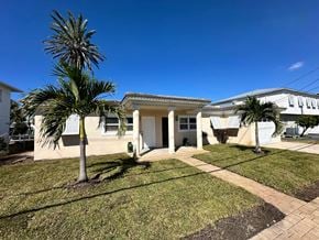 Maderia Beach apartment for rent - A house with a white exterior and a palm tree in front.