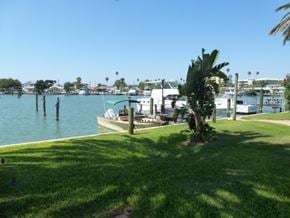 Maderia Beach apartment for rent - A boat is docked at a marina with a palm tree in the foreground.