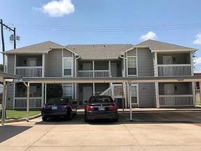 Tulsa apartment for rent - Two cars are parked in front of a two-story apartment building.