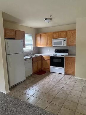 Tulsa apartment for rent - A kitchen with a white refrigerator, a white oven, and wooden cabinets.