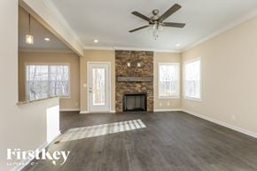Clarksville house for rent - A spacious room with a stone fireplace and a ceiling fan.