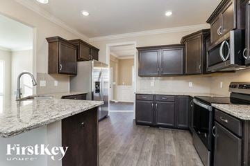 Clarksville house for rent - A kitchen with dark brown cabinets and granite countertops.