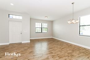 Cape Coral house for rent - A spacious room with wooden floors and a chandelier hanging from the ceiling.