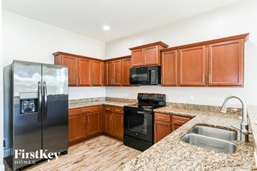 Cape Coral house for rent - A kitchen with wooden cabinets and a granite countertop.