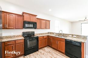 Cape Coral house for rent - A kitchen with wooden cabinets and black appliances.