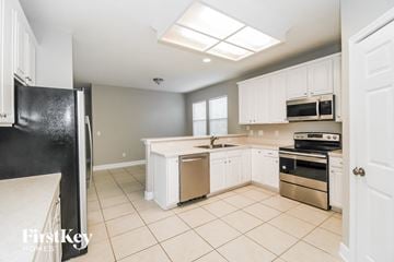 Fleming Island house for rent - A kitchen with white cabinets and a black refrigerator.