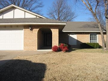Tulsa house for rent - a tan brick house with a white garage door