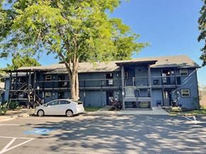 Junction City apartment for rent - A white car is parked in a parking lot in front of a grey building.