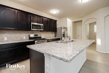 Pattison house for rent - a kitchen with granite countertops and black cabinets and a sink