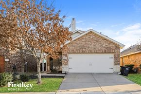 Fort Worth house for rent - A brick house with a garage and a tree with brown leaves.