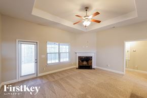 Montevallo house for rent - A spacious living room with a fireplace and a ceiling fan.