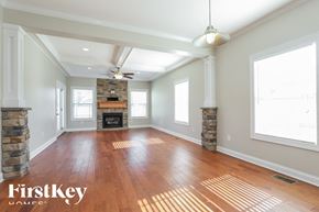 Clarksville house for rent - A spacious room with wooden floors and a stone fireplace.