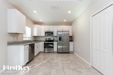 Port St. Lucie house for rent - A kitchen with white cabinets and appliances.
