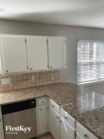 Charlotte house for rent - a kitchen with white cabinets and a granite counter top
