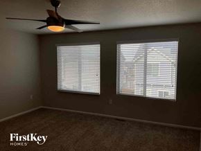 Commerce City house for rent - a living room with a ceiling fan and two windows