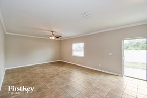 Jacksonville house for rent - an empty living room with a ceiling fan and tiled floors